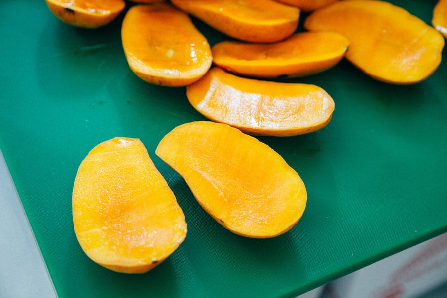 Sliced mangoes on a green chopping board